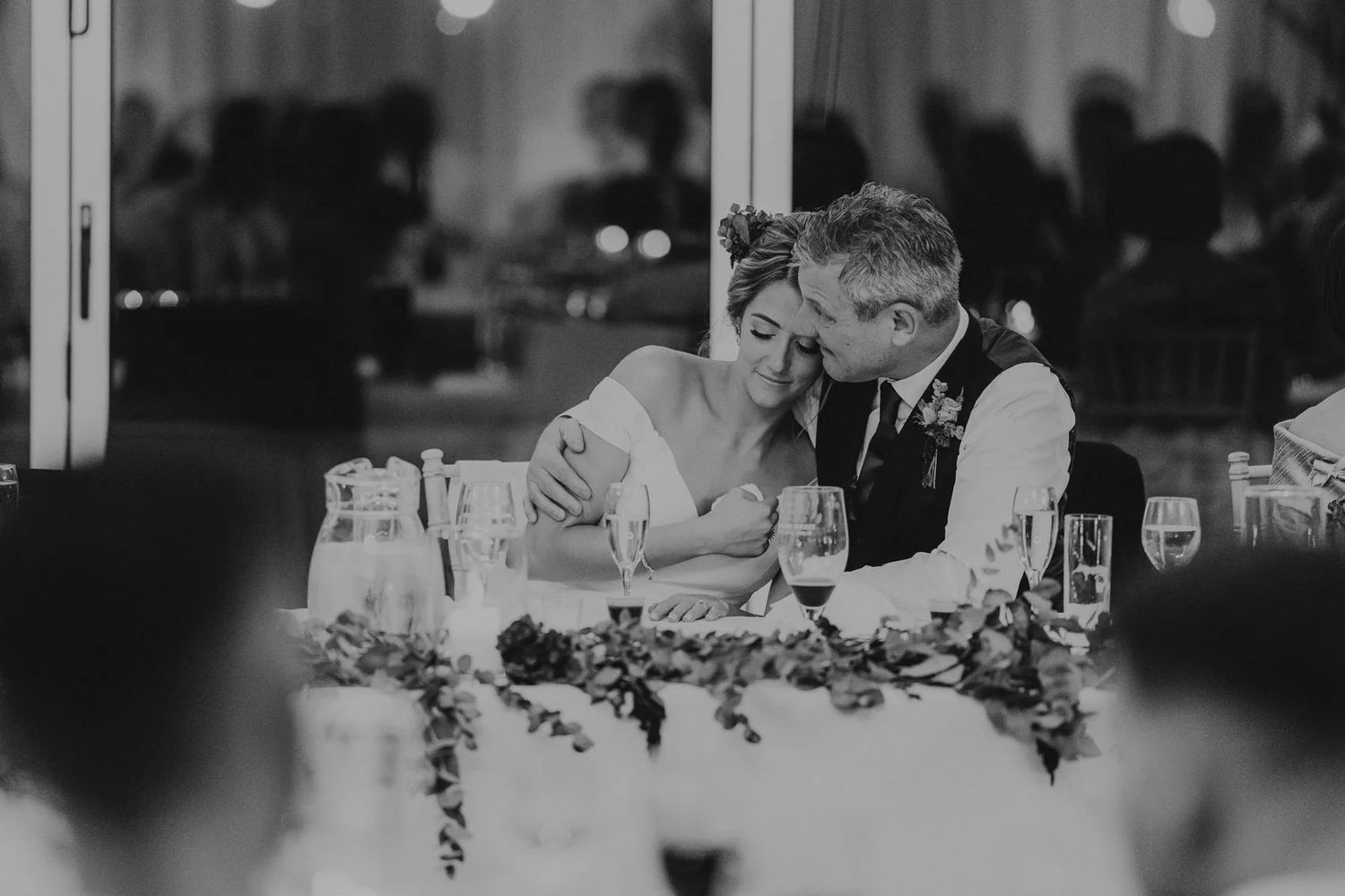 People gathered around a table at a wedding reception in a dimly lit venue.