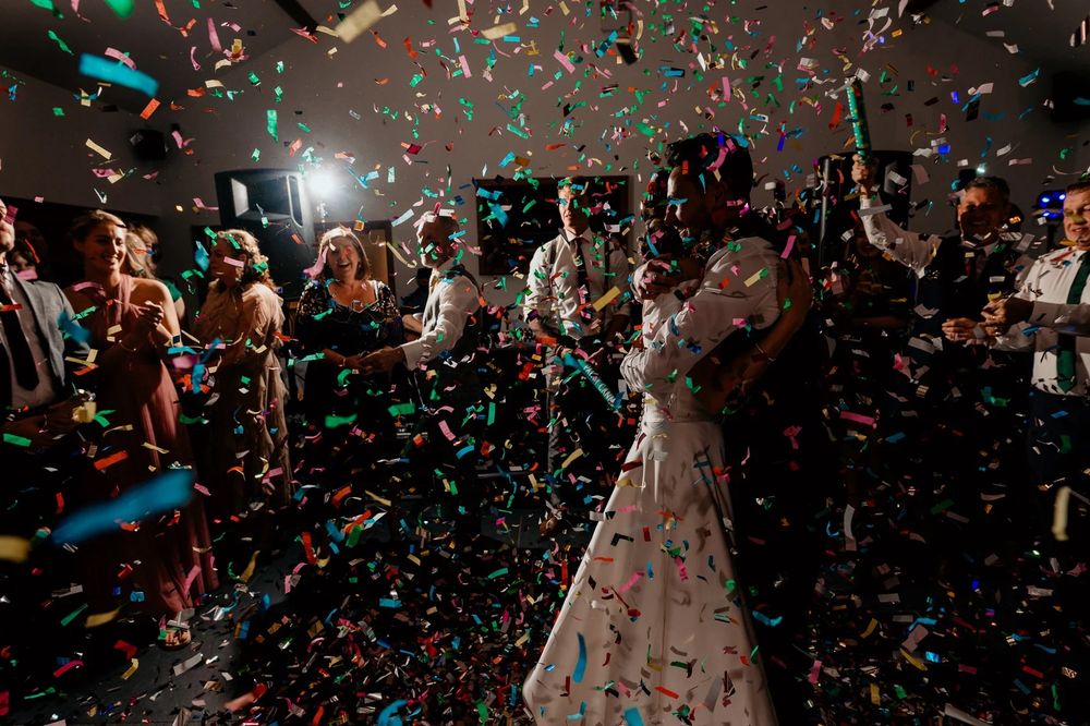 Dancing silhouettes and falling confetti create a festive atmosphere at a celebratory event.