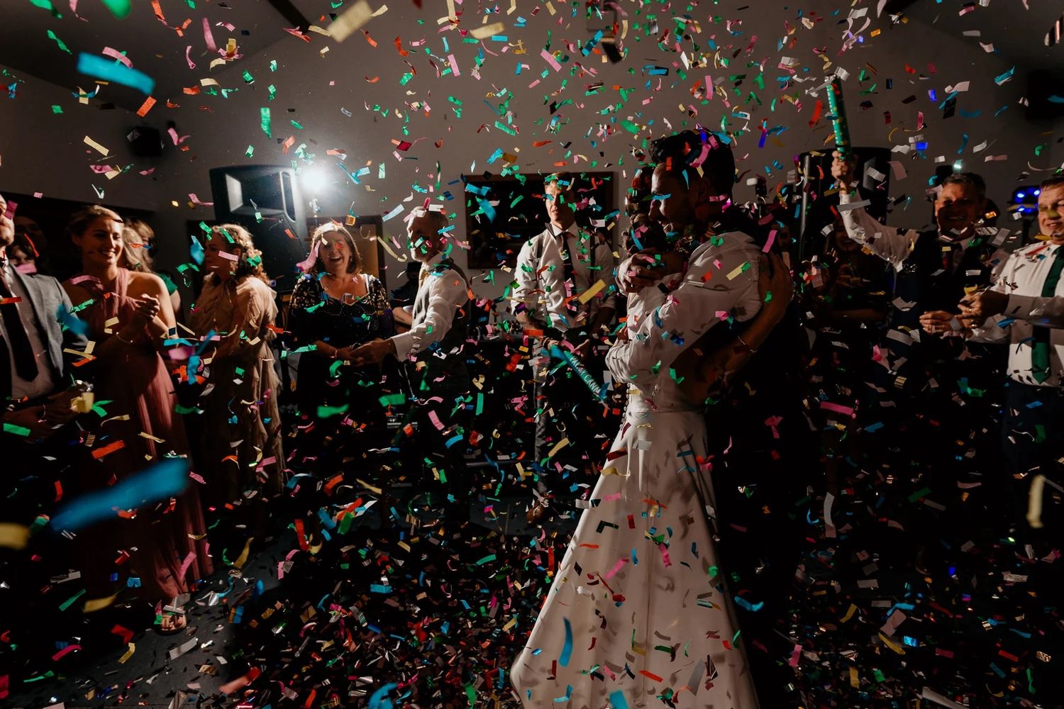 Dancing silhouettes and falling confetti create a festive atmosphere at a celebratory event.