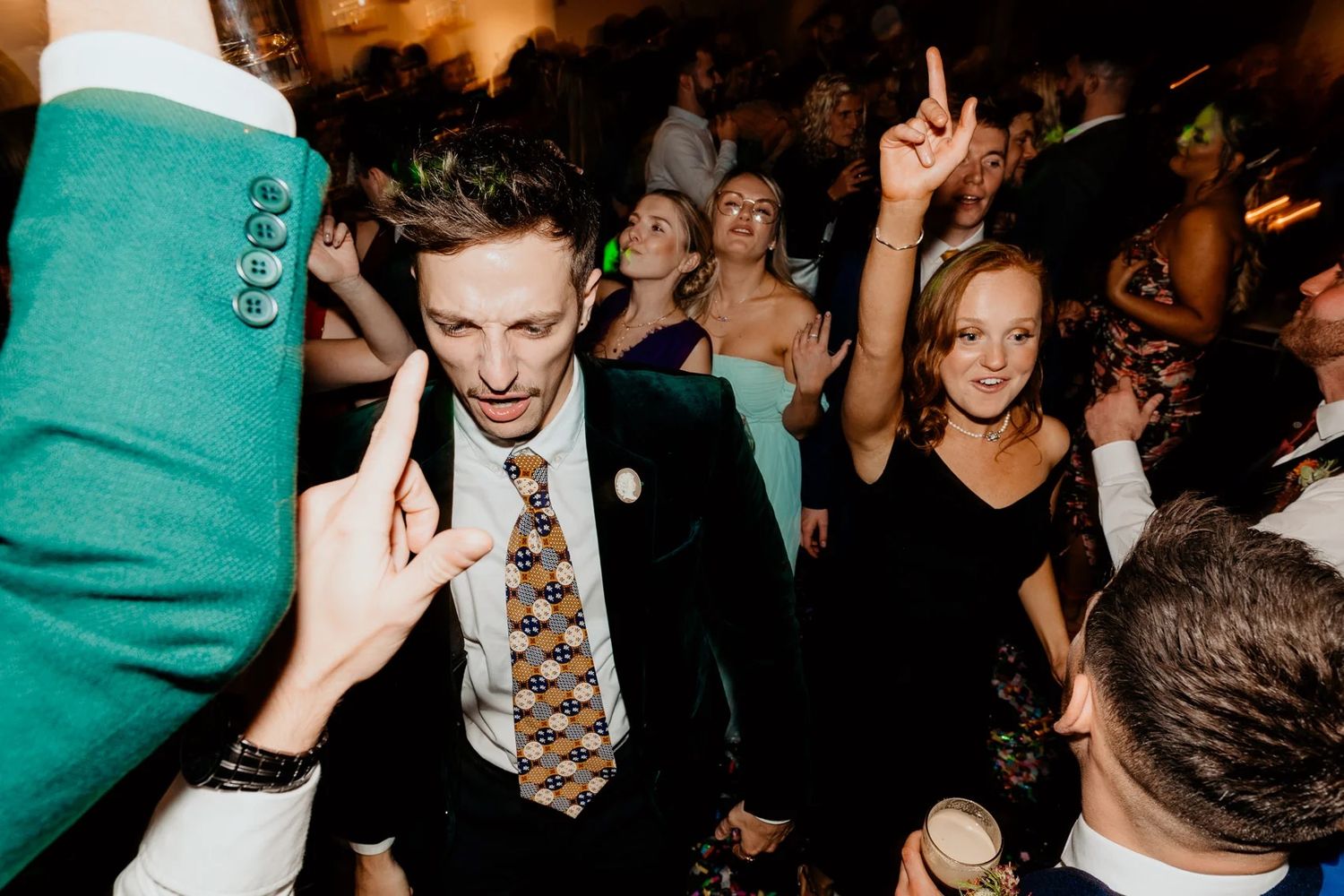 Party guests dance and celebrate under warm lighting at a lively reception.