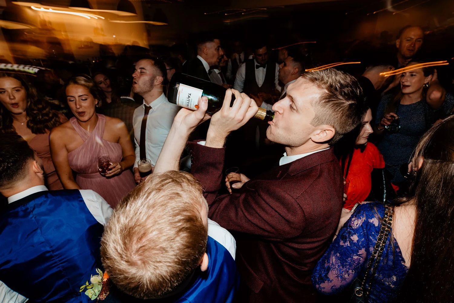 Energetic wedding reception dancing with guests singing and celebrating at night.