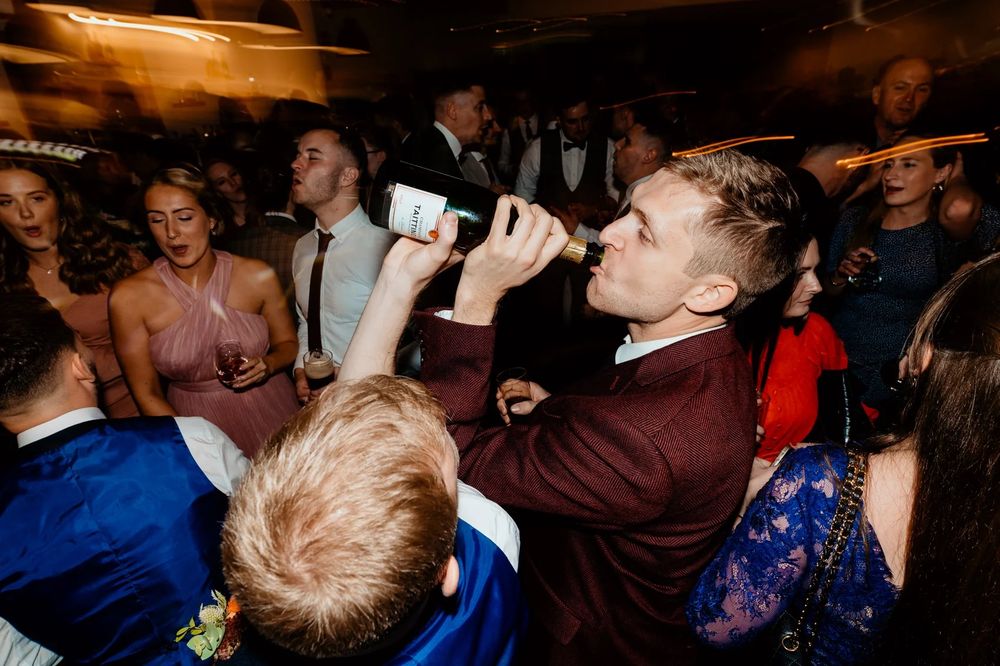 Energetic wedding reception dancing with guests singing and celebrating at night.