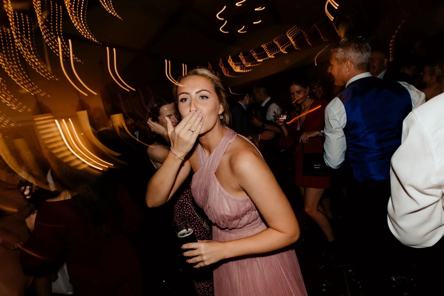 Dark and moody dance floor scene at a wedding reception with ambient lighting.