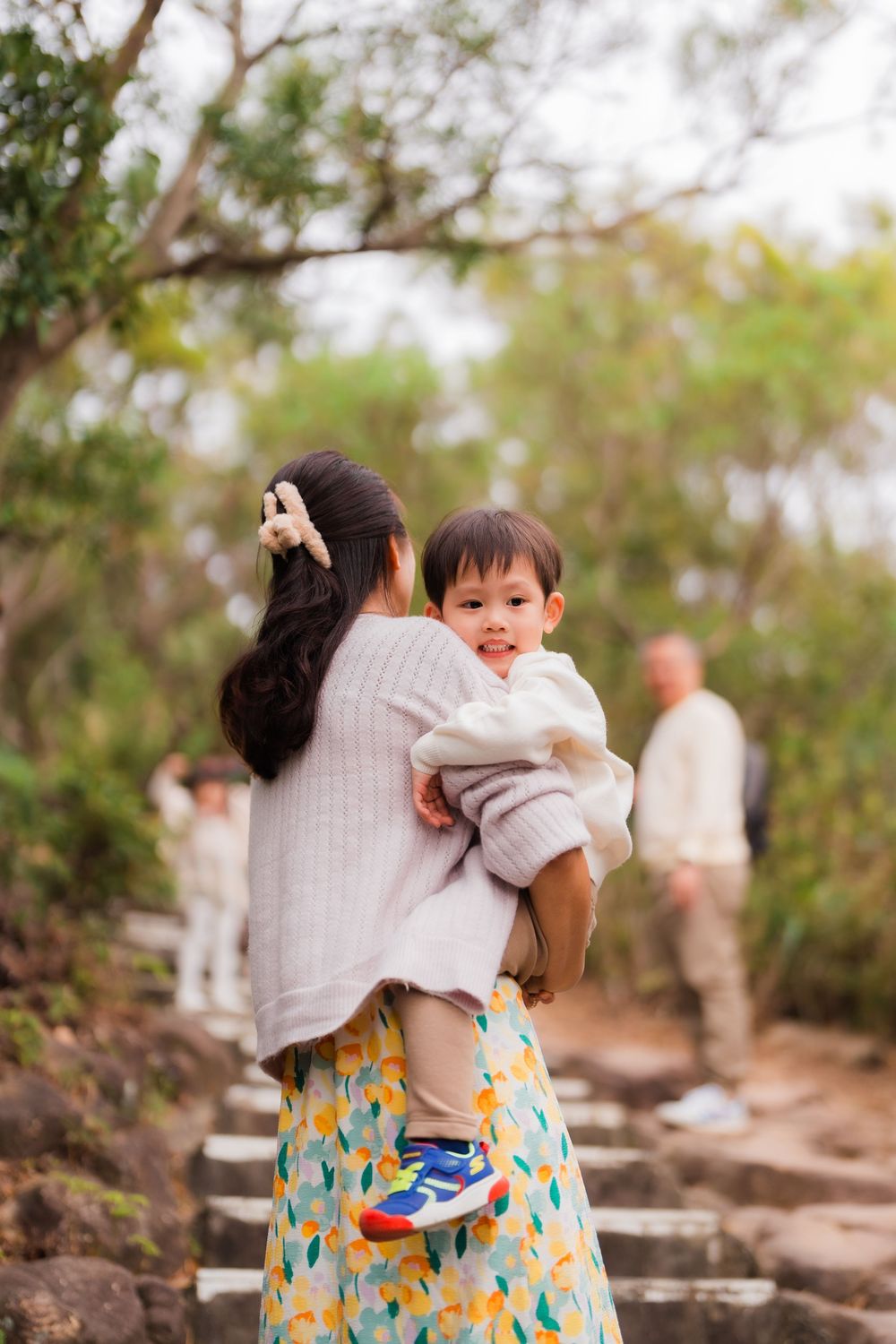 Mom carrying child up steps with family at Taipei Battleship Rock