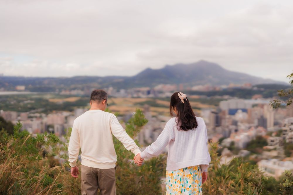 Couple holding hands overlooking Taipei City from Battleship Rock Hiking Trail peak.