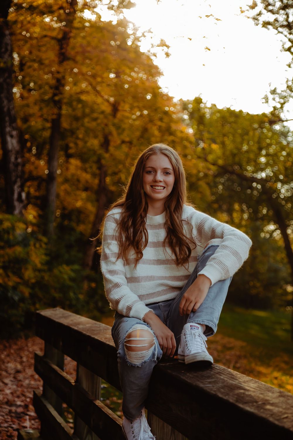 Candid autumn photoshoot moments captured on a wooden bench surrounded by fall foliage at sunset.
