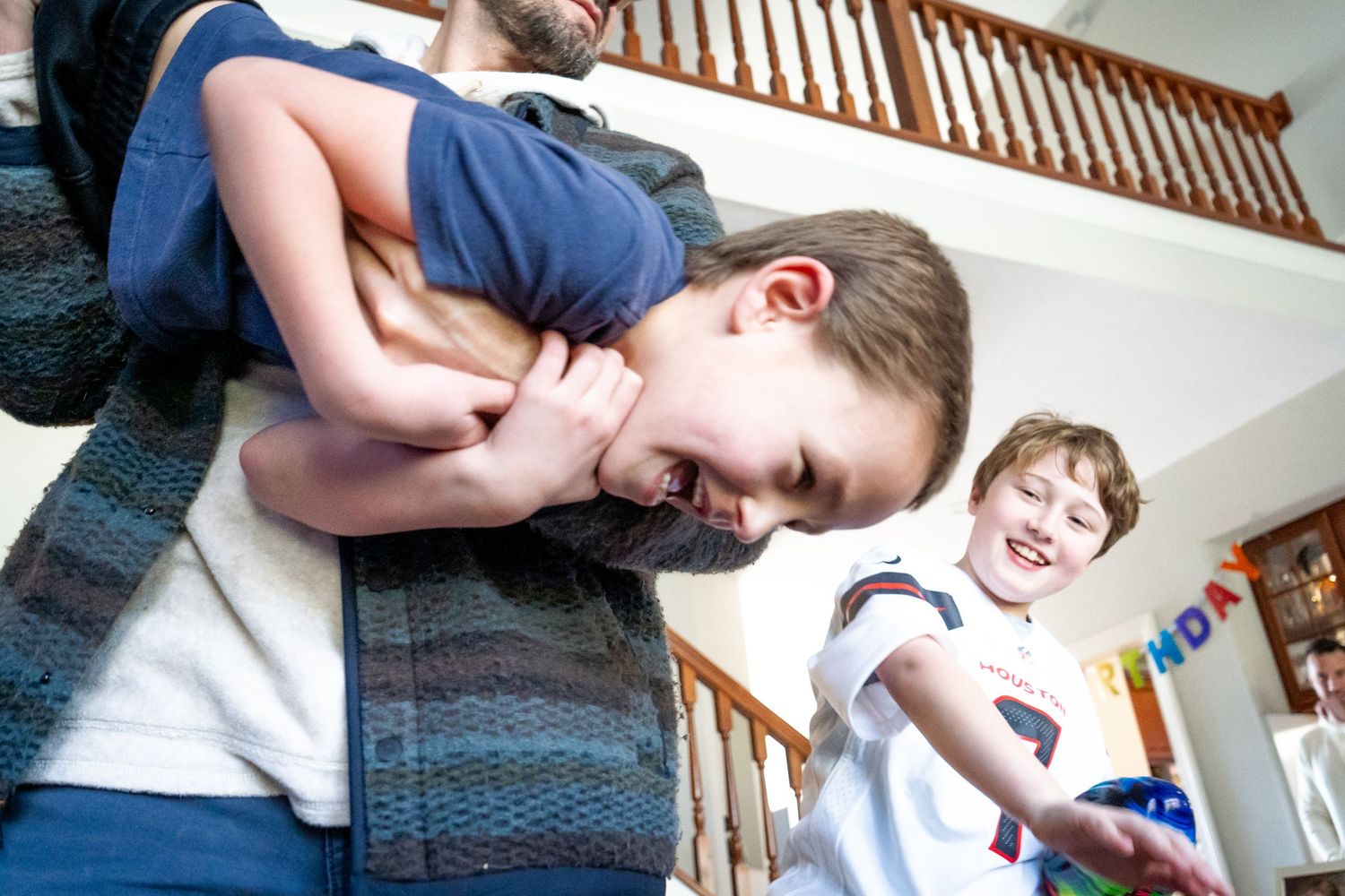 a child laughing while being swung around while another child smiles in the background