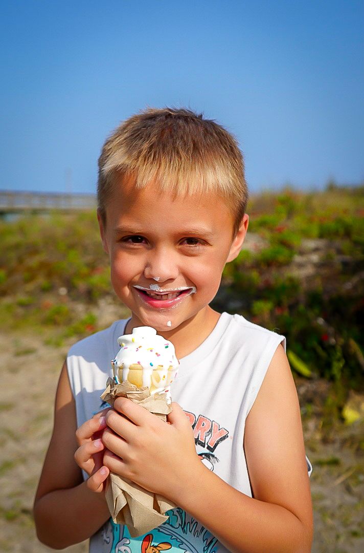 Someone enjoying vanilla ice cream with sprinkles outdoors on a bright, sunny day.