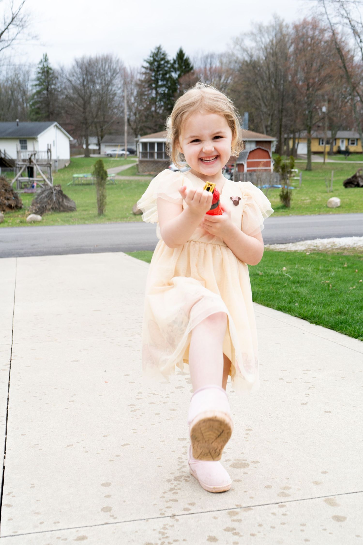 showing a playful moment on a sunny spring day with grass and trees in background.
