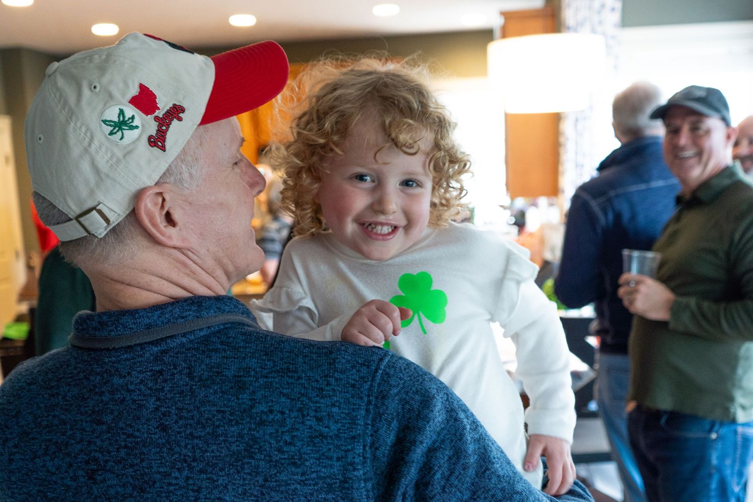 People gathering together at a st Patricks day party with festive decorations in the background.