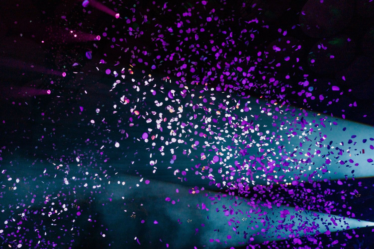 Concert arena filled with purple confetti falling from ceiling during live performance.