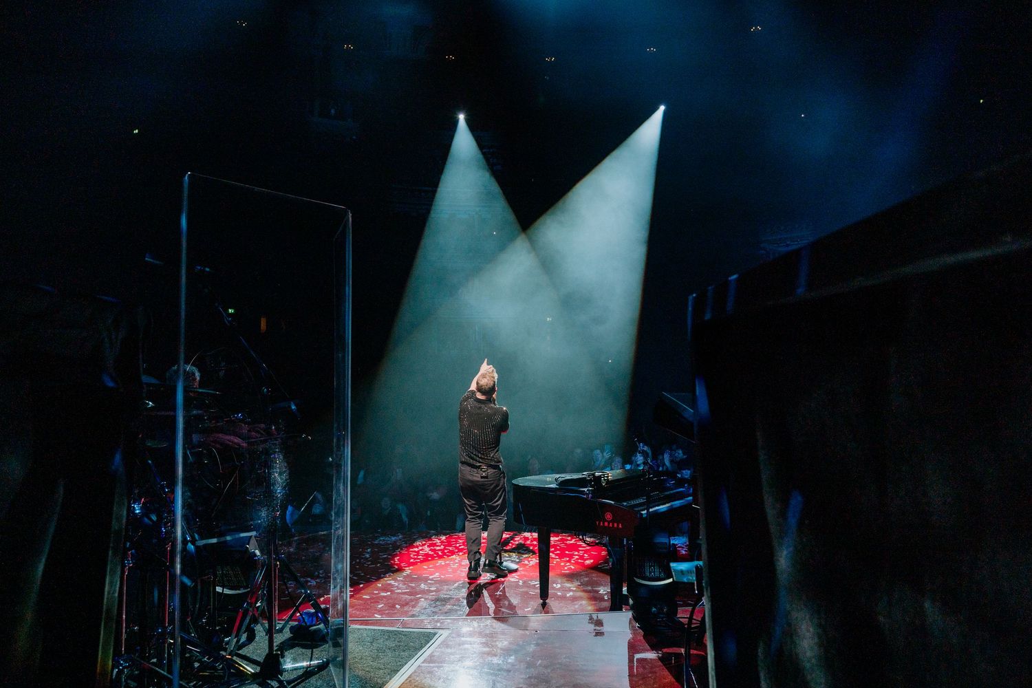 Dark concert stage illuminated by dramatic blue spotlights and fog effects.