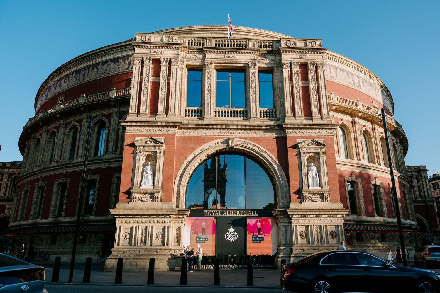 Panoramic exterior shot of Royal Albert Hall's historic architecture under blue sky.