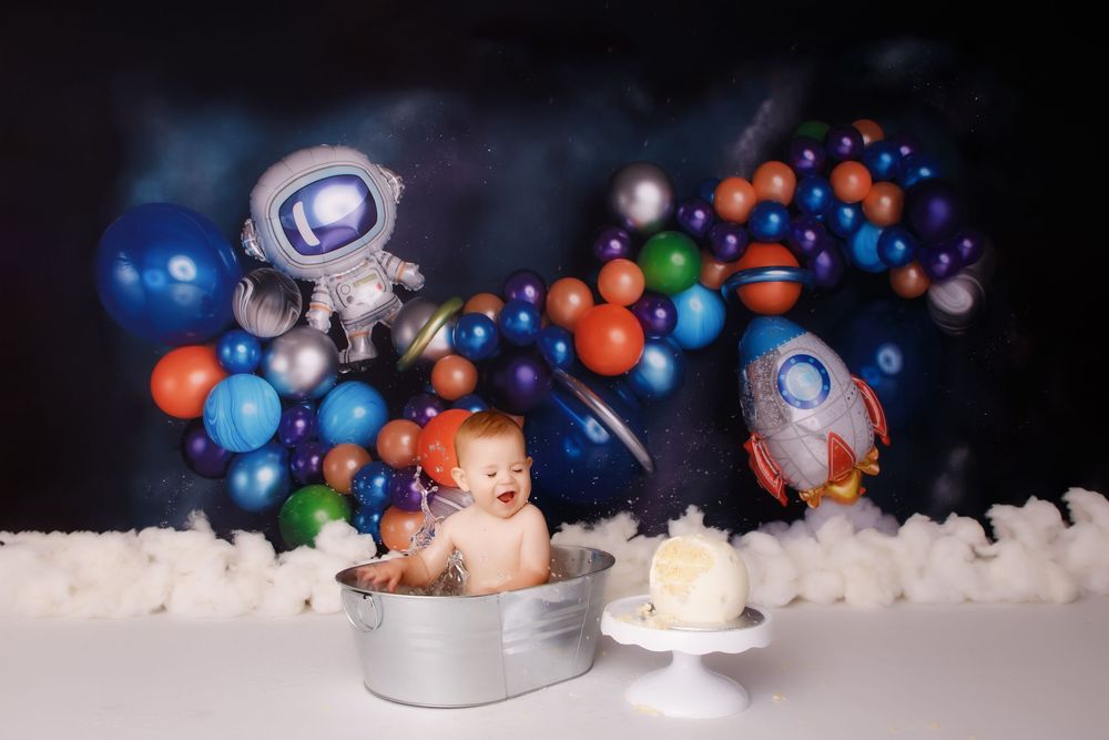 Multiple baby portraits against a dark backdrop with floating colorful bubbles and decorative props create a dreamy scene.