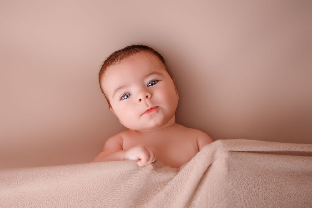 Seven soft and dreamy photos of a newborn baby arranged in a filmstrip style collage with pink tones.