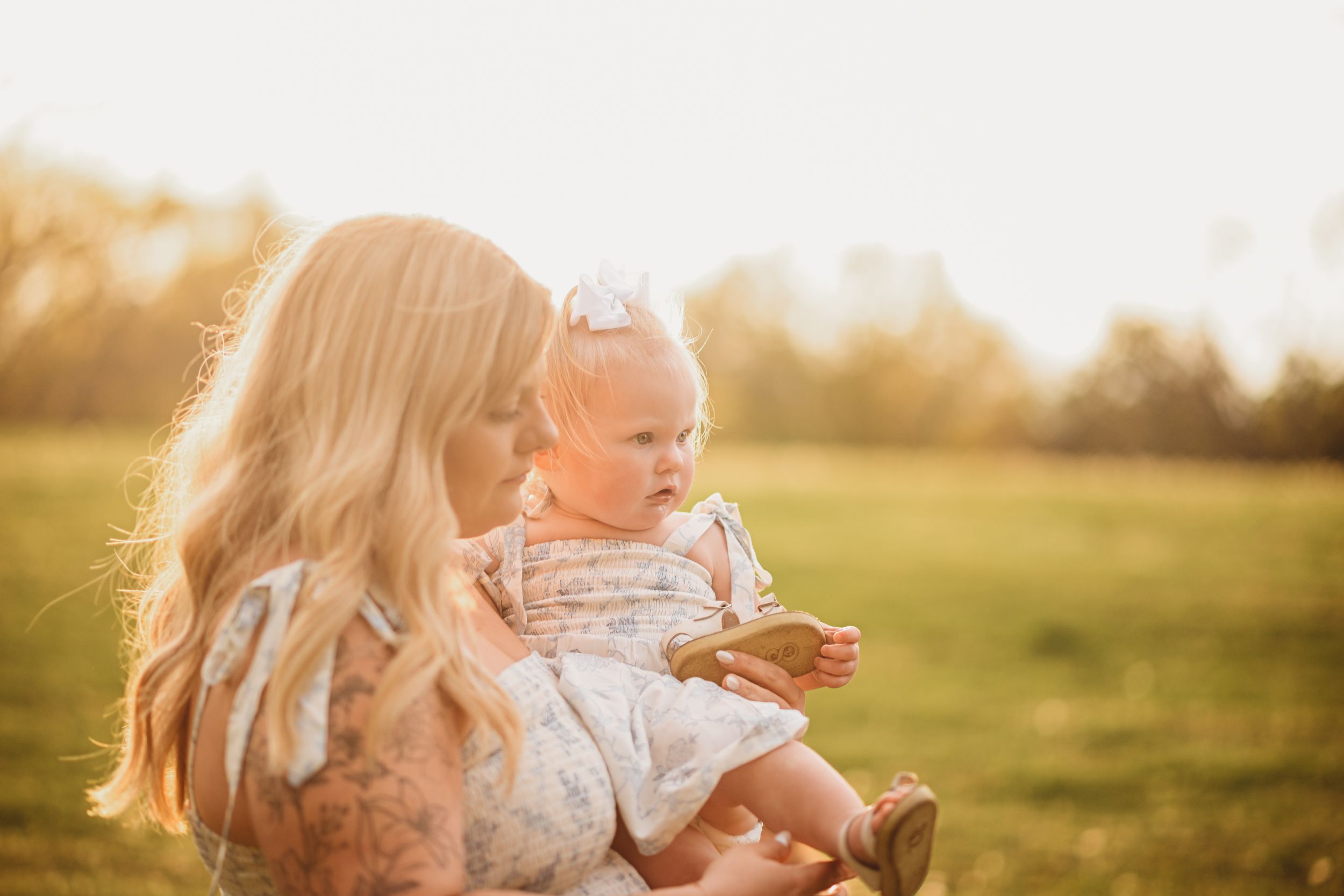 Family enjoying a playful moment together in a sun-drenched meadow at golden hour.