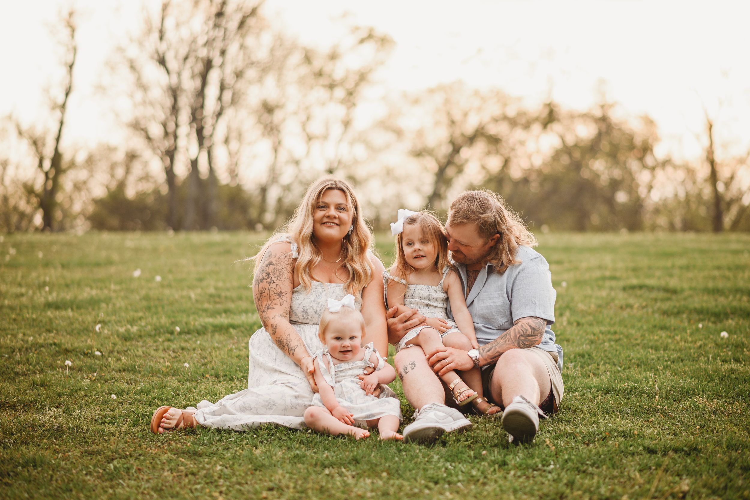 Family group relaxing on grass during golden hour photography session.