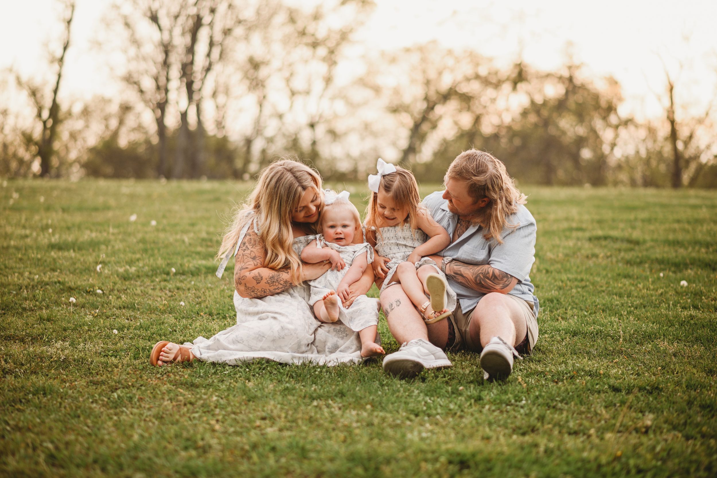 Family members sitting close together on grass during outdoor photo session.