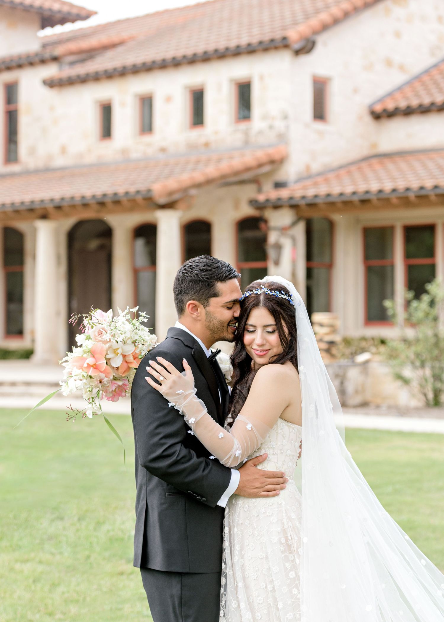 Newlywed bride and groom share a sweet moment in an outdoor garden with Spanish-style architecture at Garey House in Georgetown, TX.