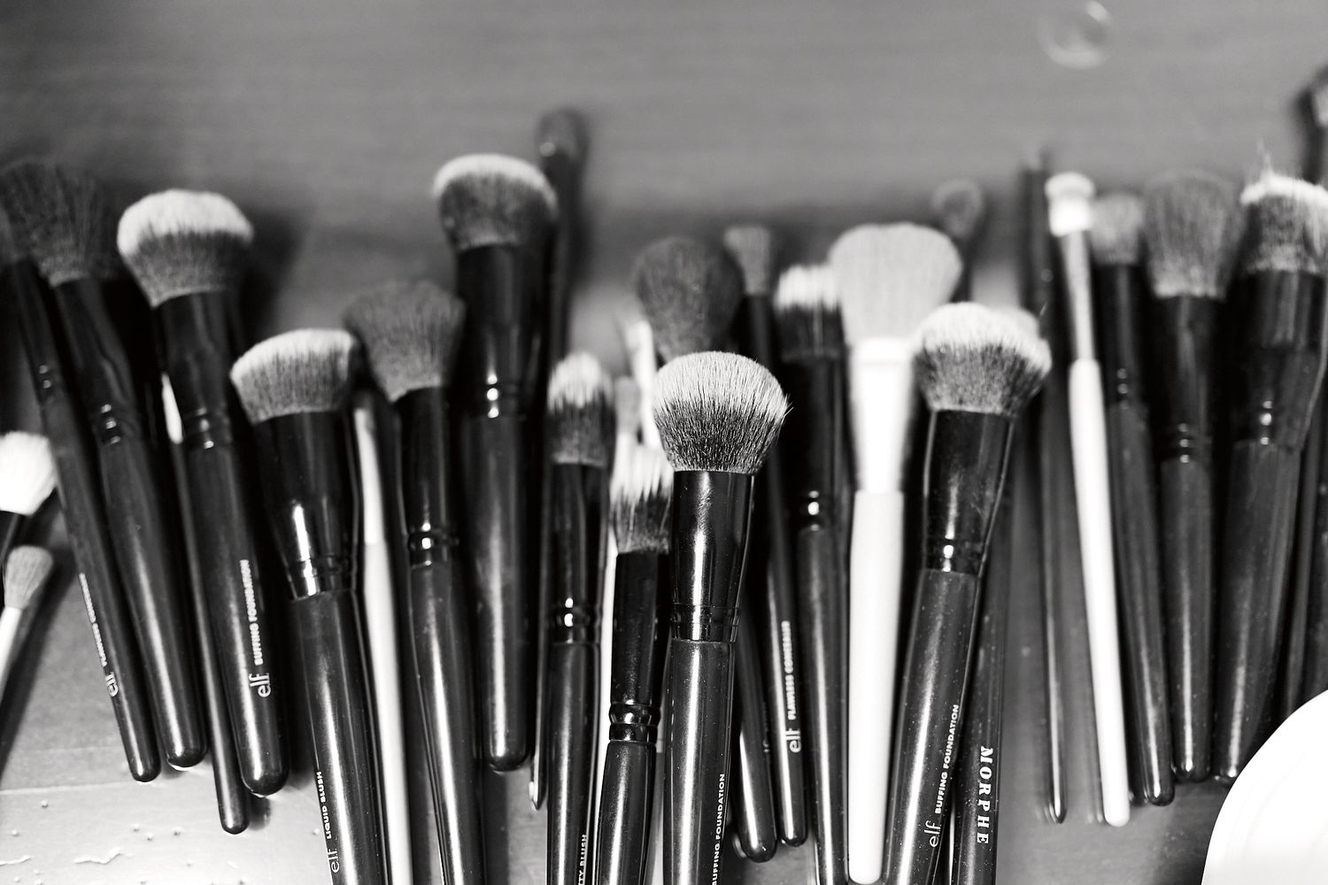 Collection of black and white makeup brushes arranged in a row showing various brush types and bristles.