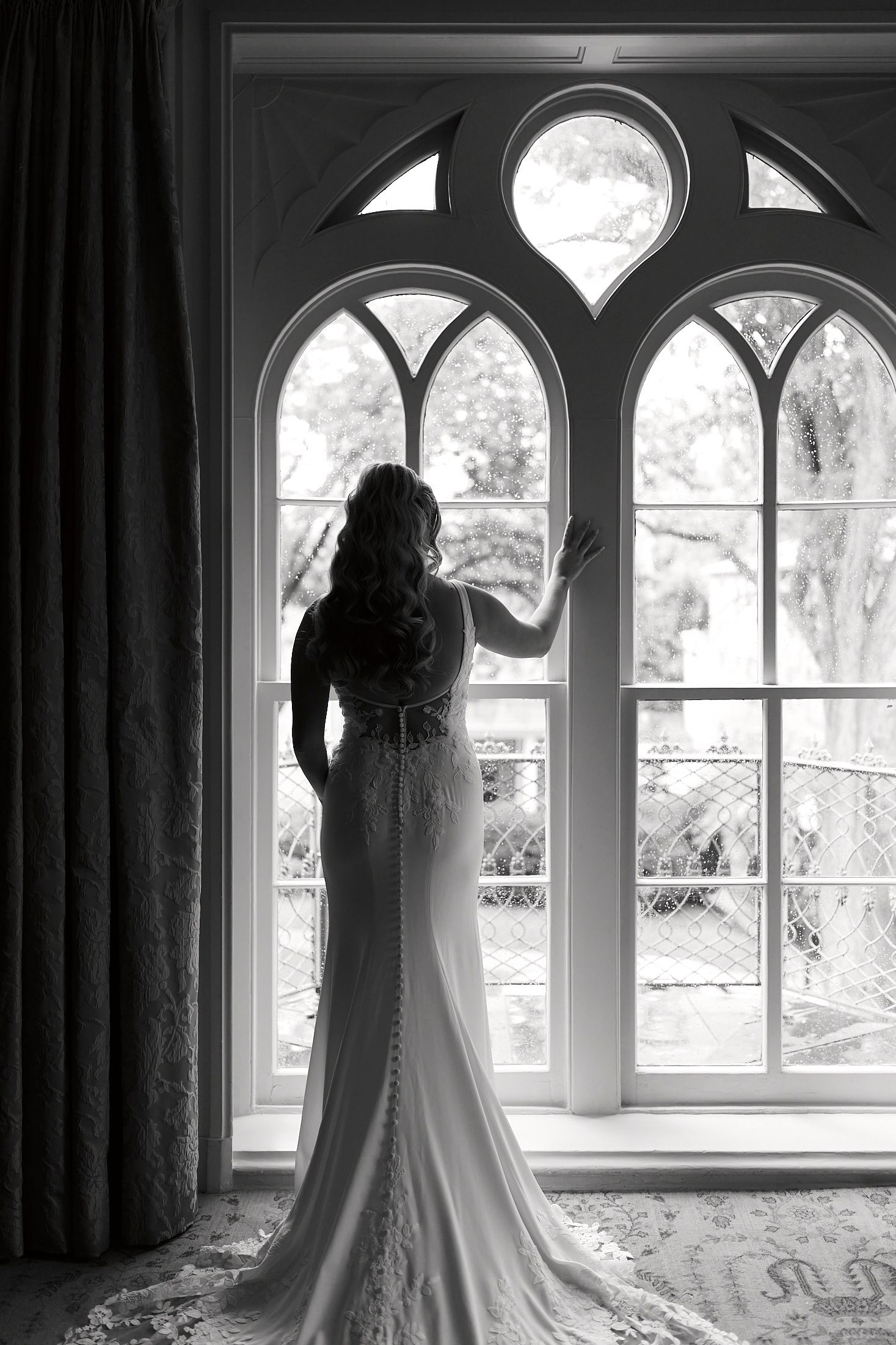 Black and white portraits showcase a beautiful wedding dress silhouette against arched windows in an elegant setting.