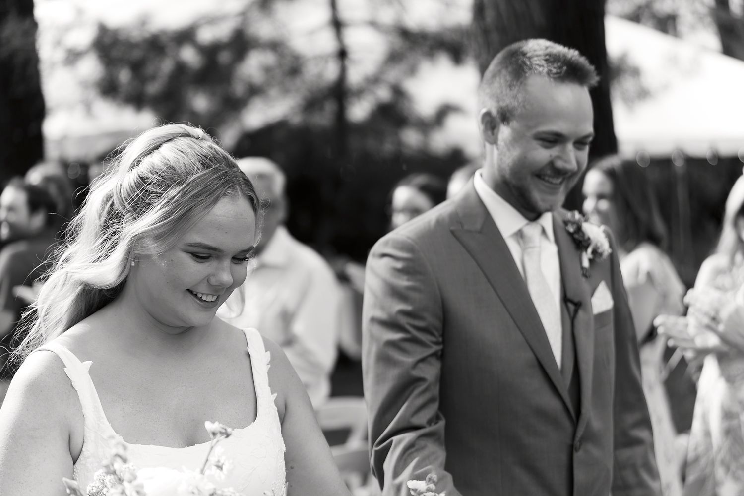 Wedding party celebrates outdoors with joyful expressions and formal attire.