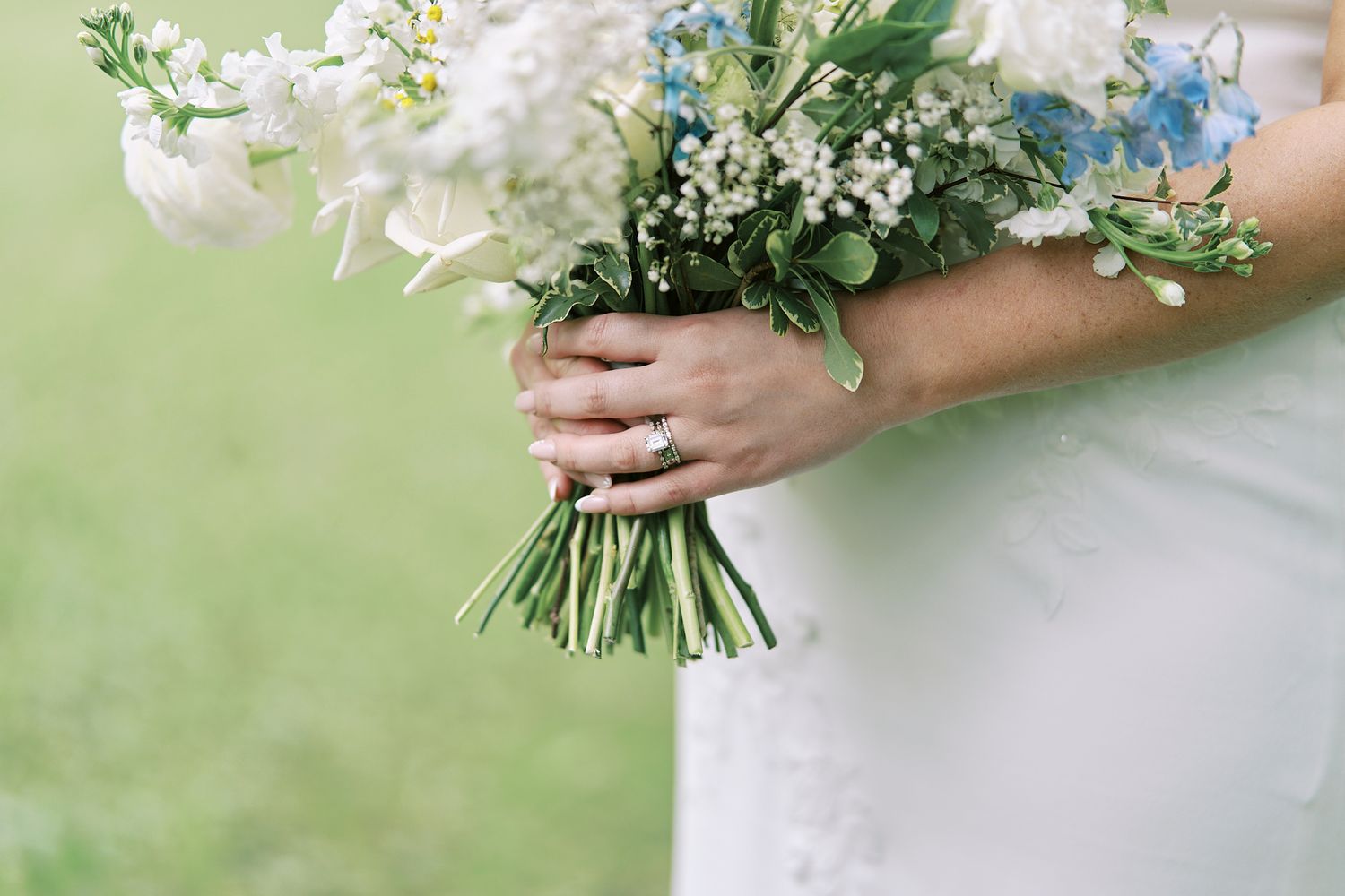 A collection of elegant white floral wedding bouquets arranged with lush greenery against a soft blurred background.