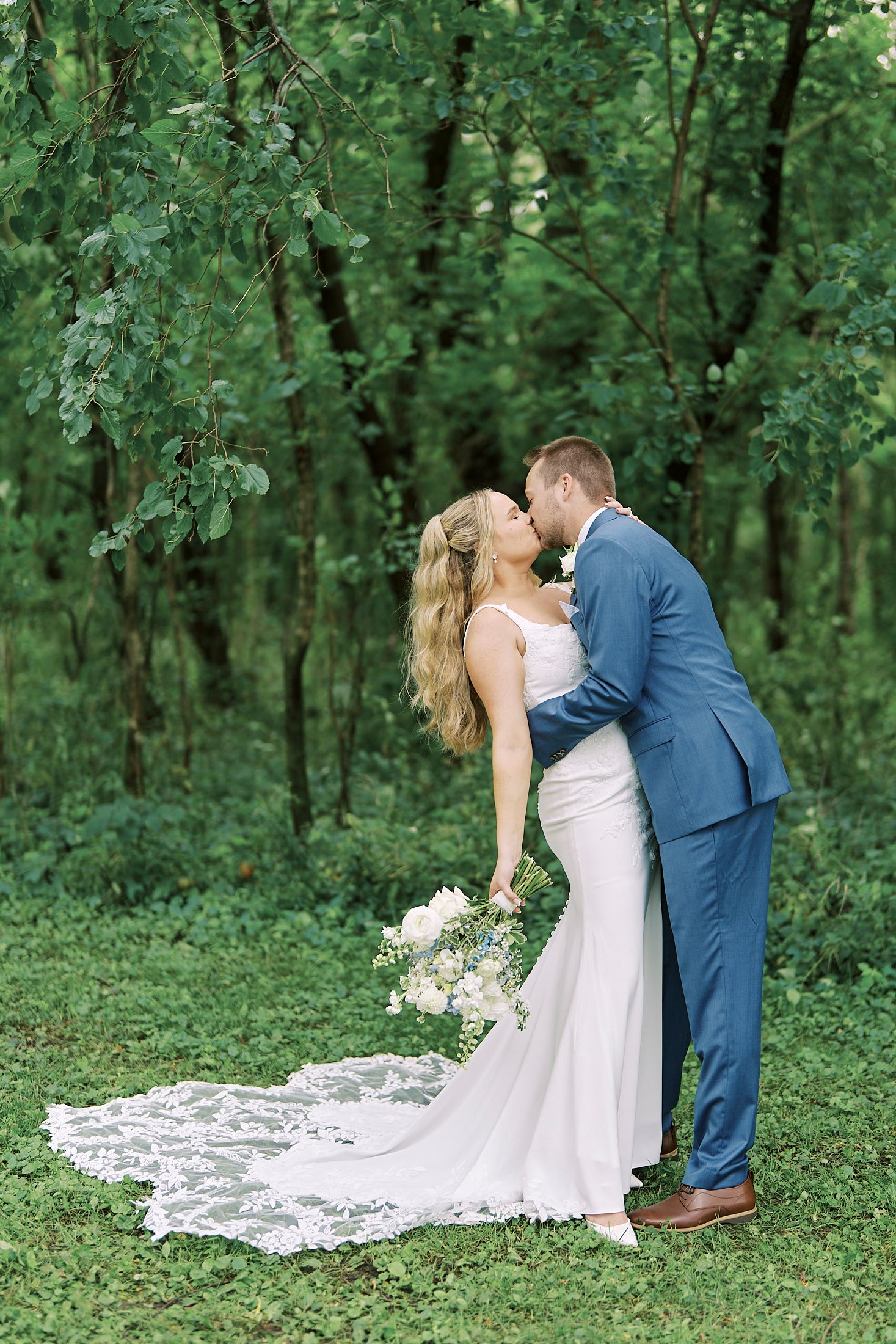 Romantic wedding portraits in lush green forest setting with flowing white dress.