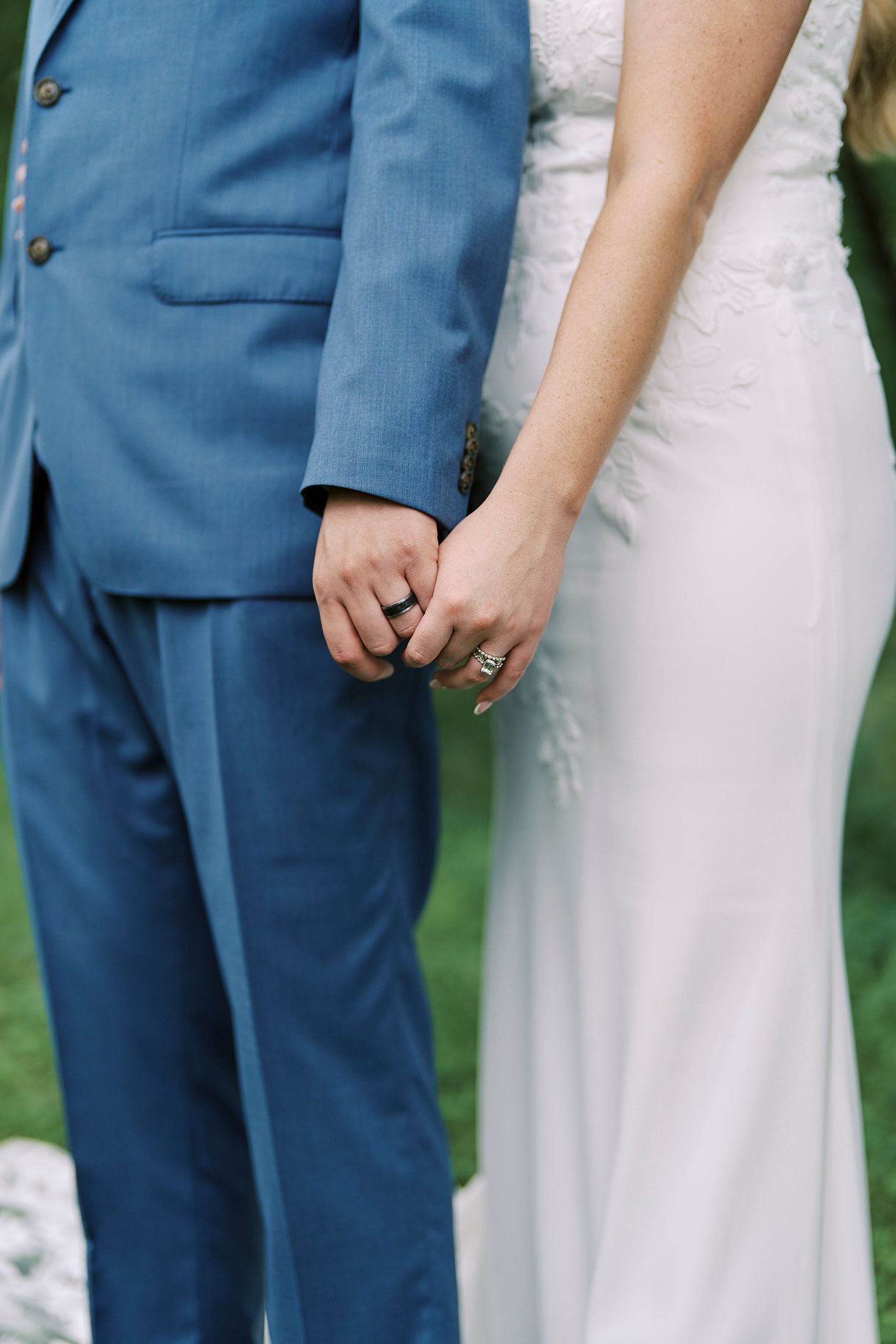 Close-up detail of blue suit and white dress during wedding ceremony.