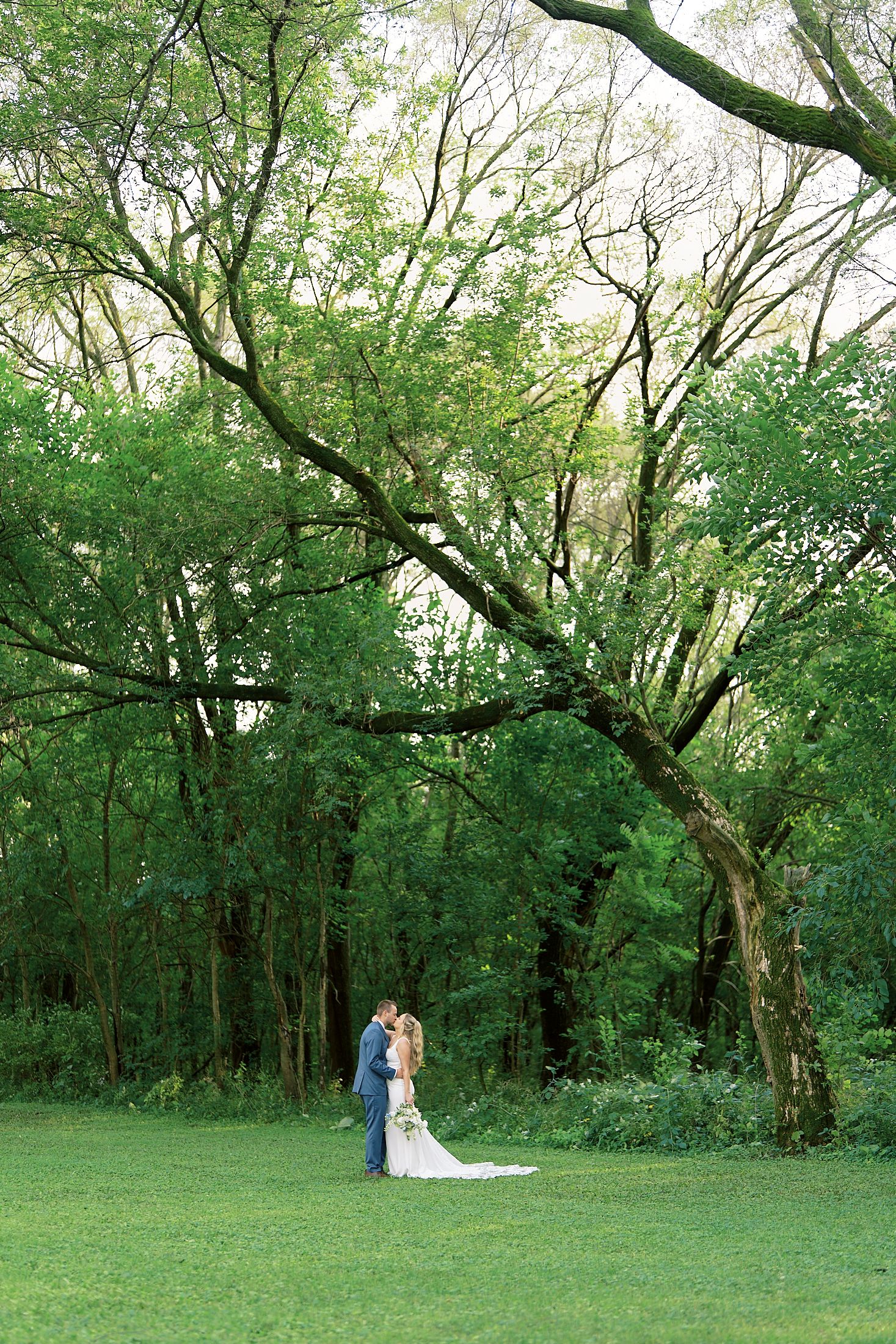 Wedding couple walking through a lush green wooded area on their special day.