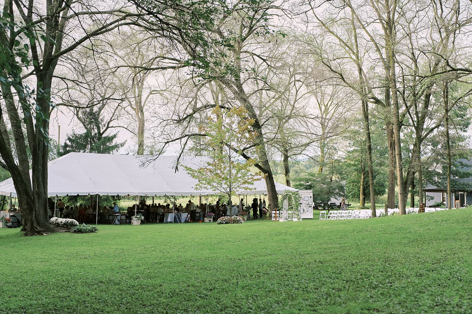 Scenic spring garden landscape with green lawns, mature trees and a white structure visible in the background.