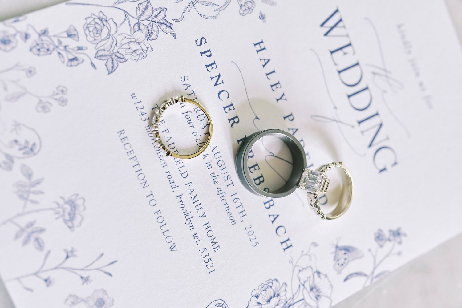 Wedding invitations and delicate pearl accessories arranged on a white floral background with elegant typography details.
