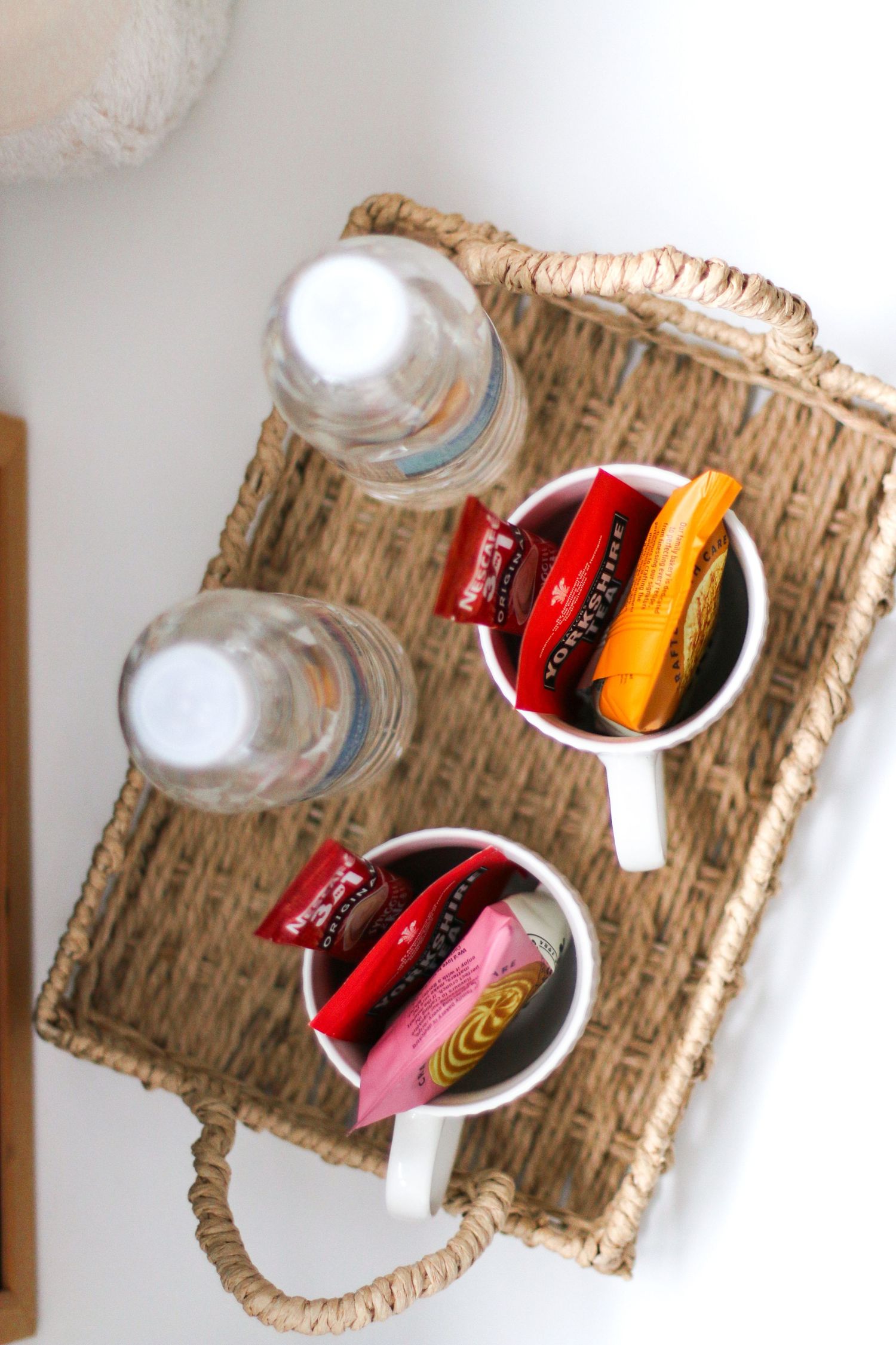 Overhead view of wicker tray with water bottles and white mugs containing red and orange tea bags during newborn shoot in Nottingham