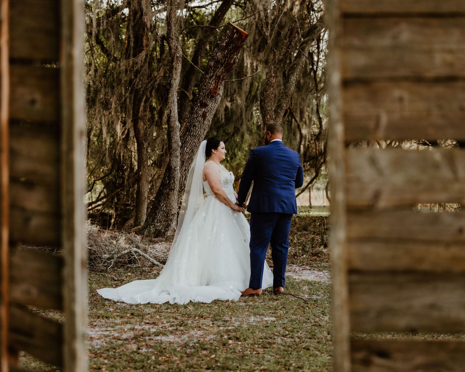 Married couple in rustic wooden outdoor setting with hanging moss. First look Candid Wedding Photographer. Central Florida Wedding Venue