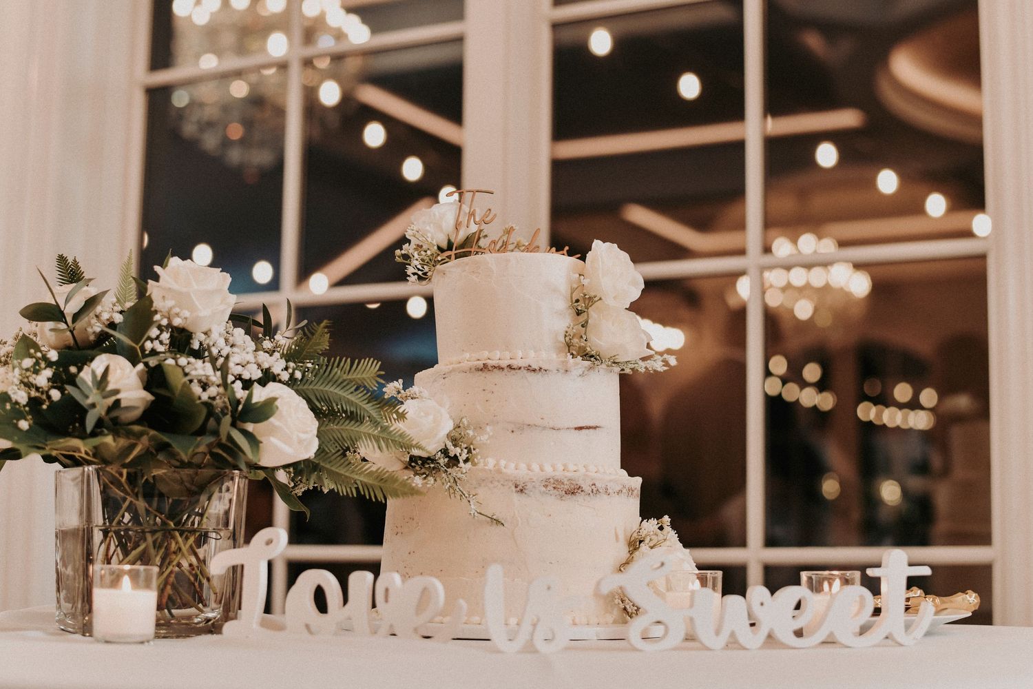 a warm lit photo of the elegant cake table of the hillside estate wedding venue