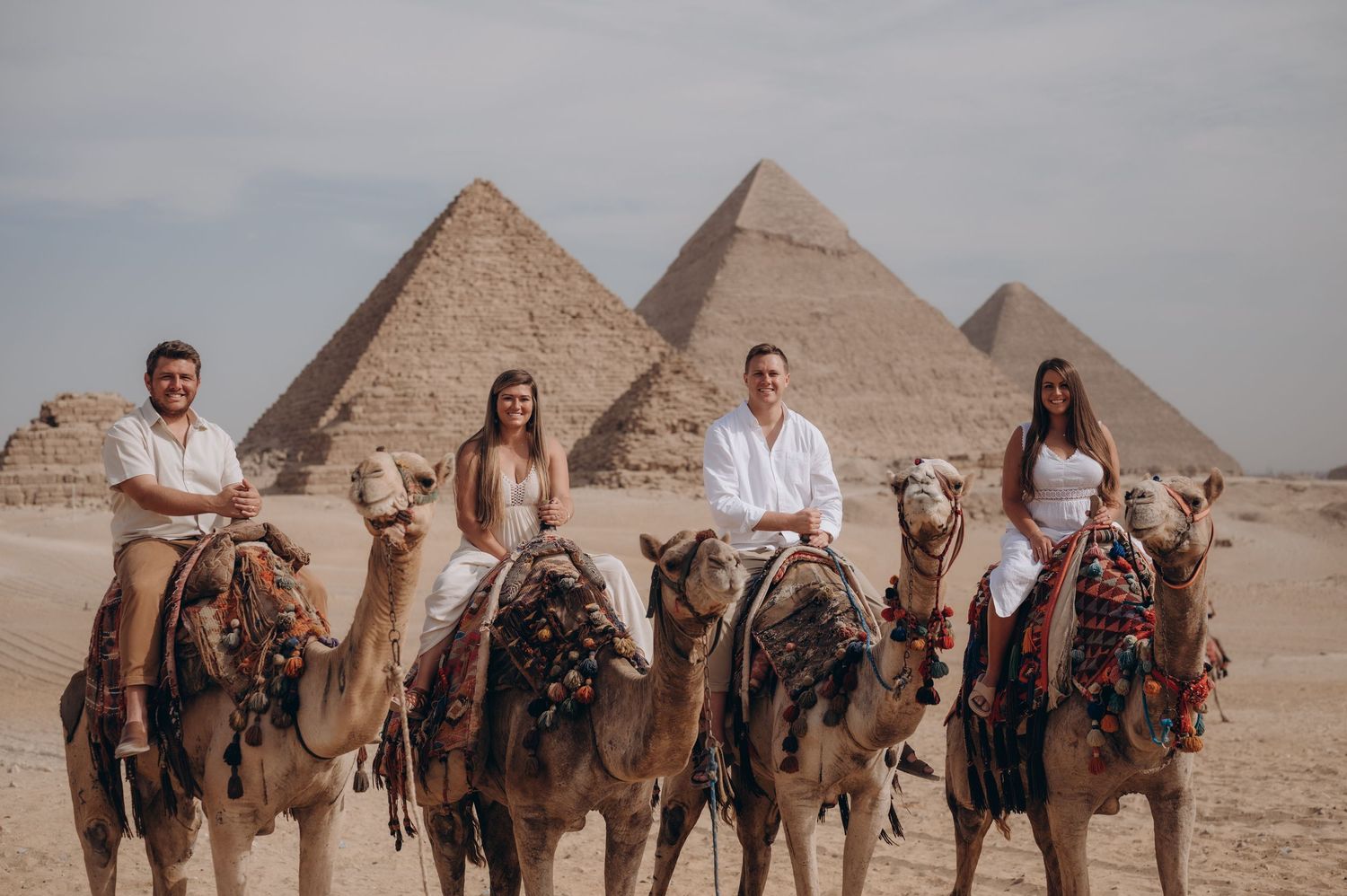 Group riding decorated camels in front of the majestic Pyramids of Giza in Egypt.