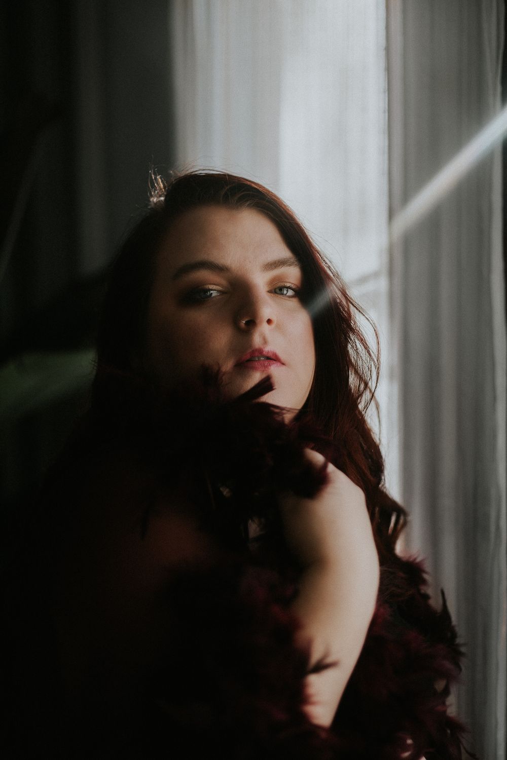 Dramatic portrait series featuring dark shadows and moody lighting near window.