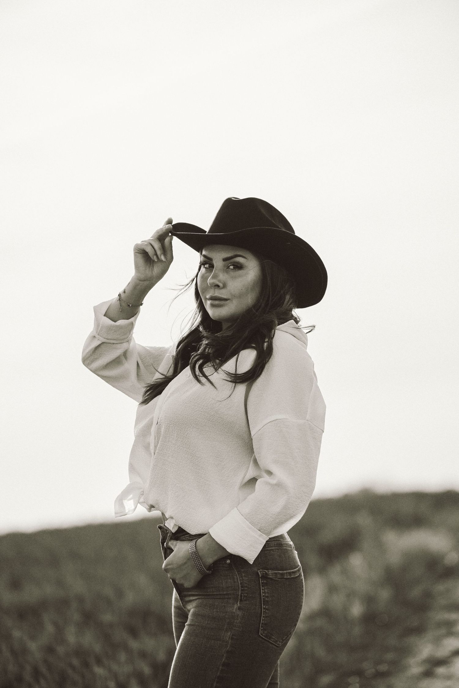 Kreativt porträtt Skåne – kvinna i cowboyhatt och vit skjorta i svartvitt foto | Konstnärlig fotograf Malmö