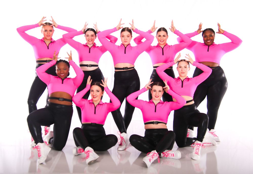 Group performance featuring dancers in pink tops and black pants striking dynamic poses.