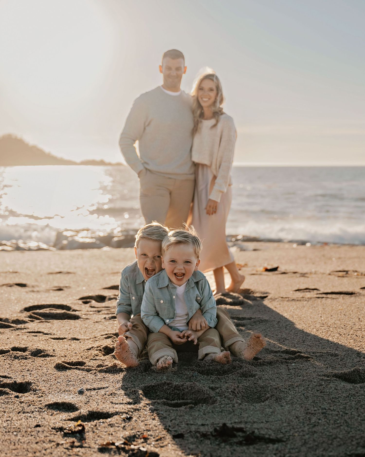 Family enjoying a sunny day at the beach with mountains in background.