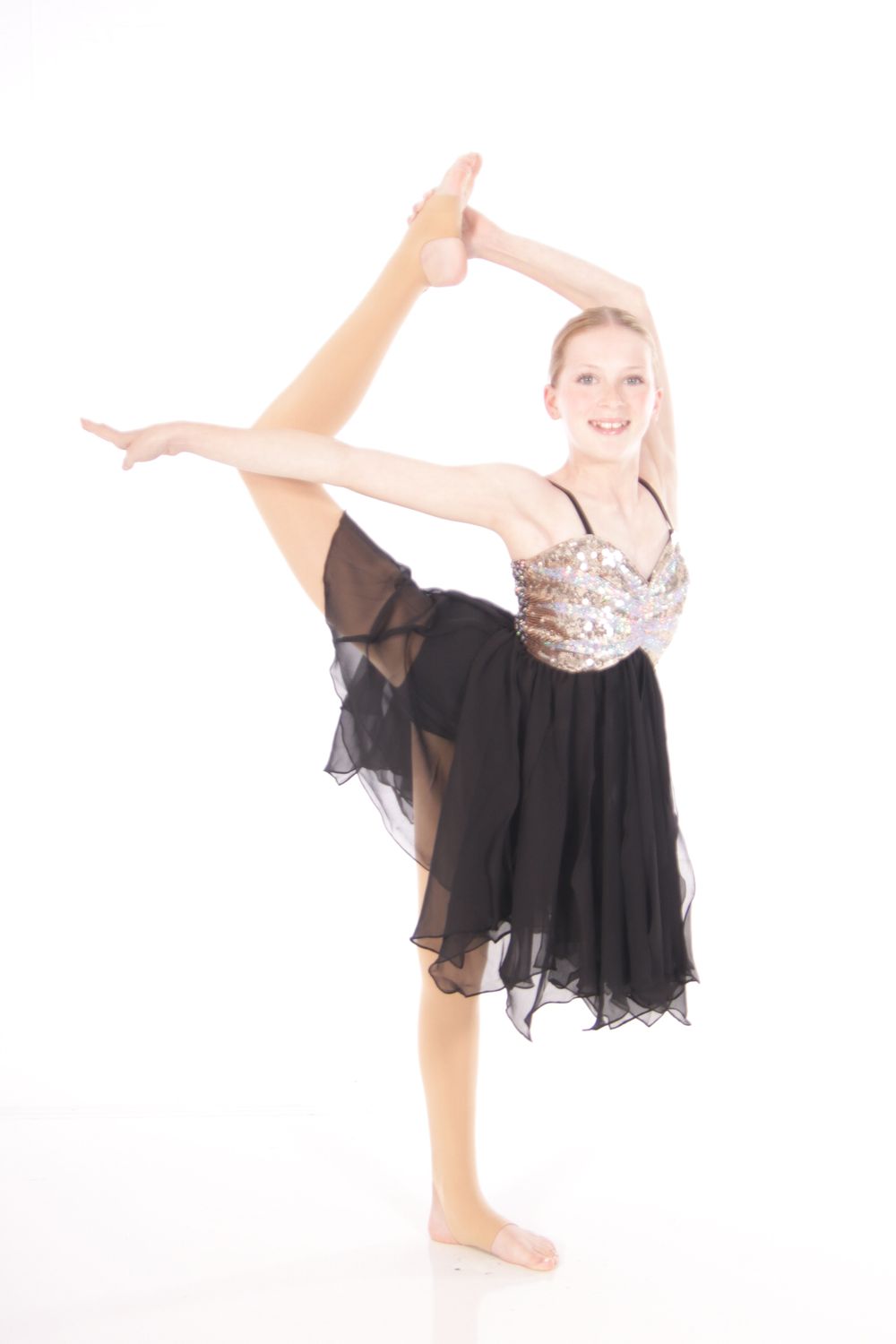 Dancer in black dress performs expressive high kick sequence against white backdrop.