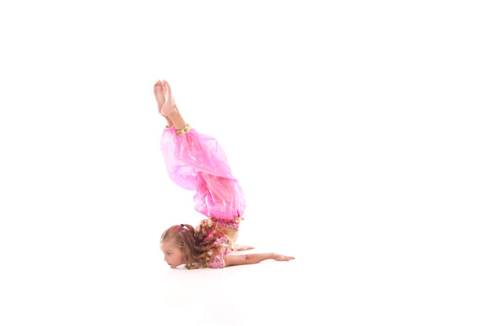 Dancers leap and twirl in pink costumes against white backdrop.