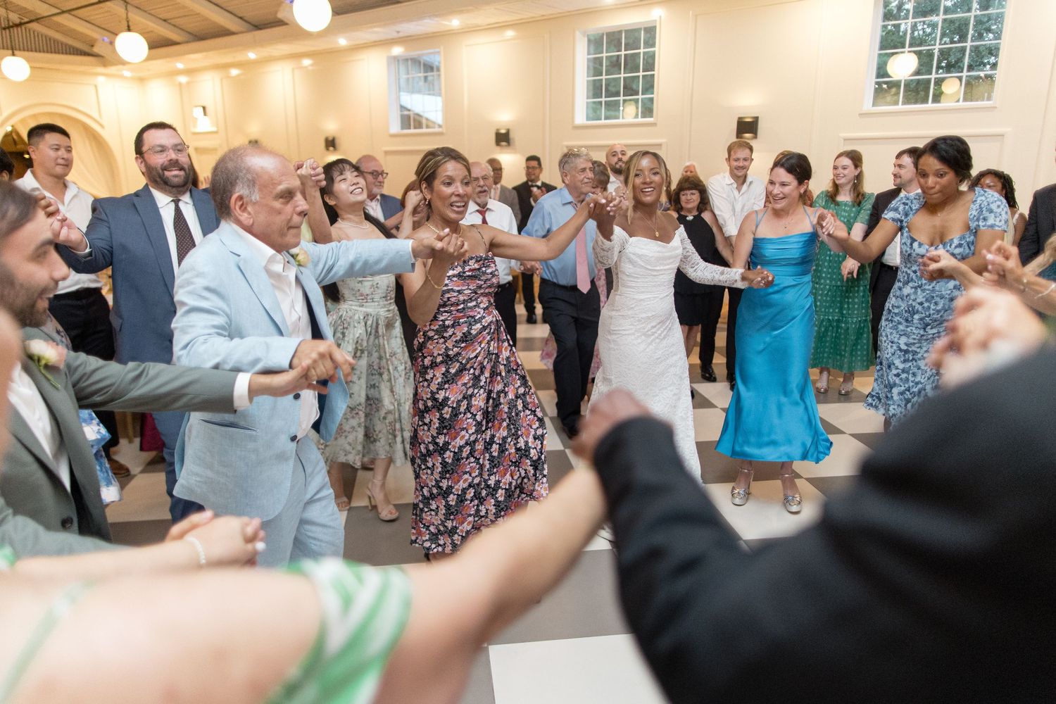 Wedding guests dance together and celebrate during the reception as they enjoy the festivities on the dance floor.