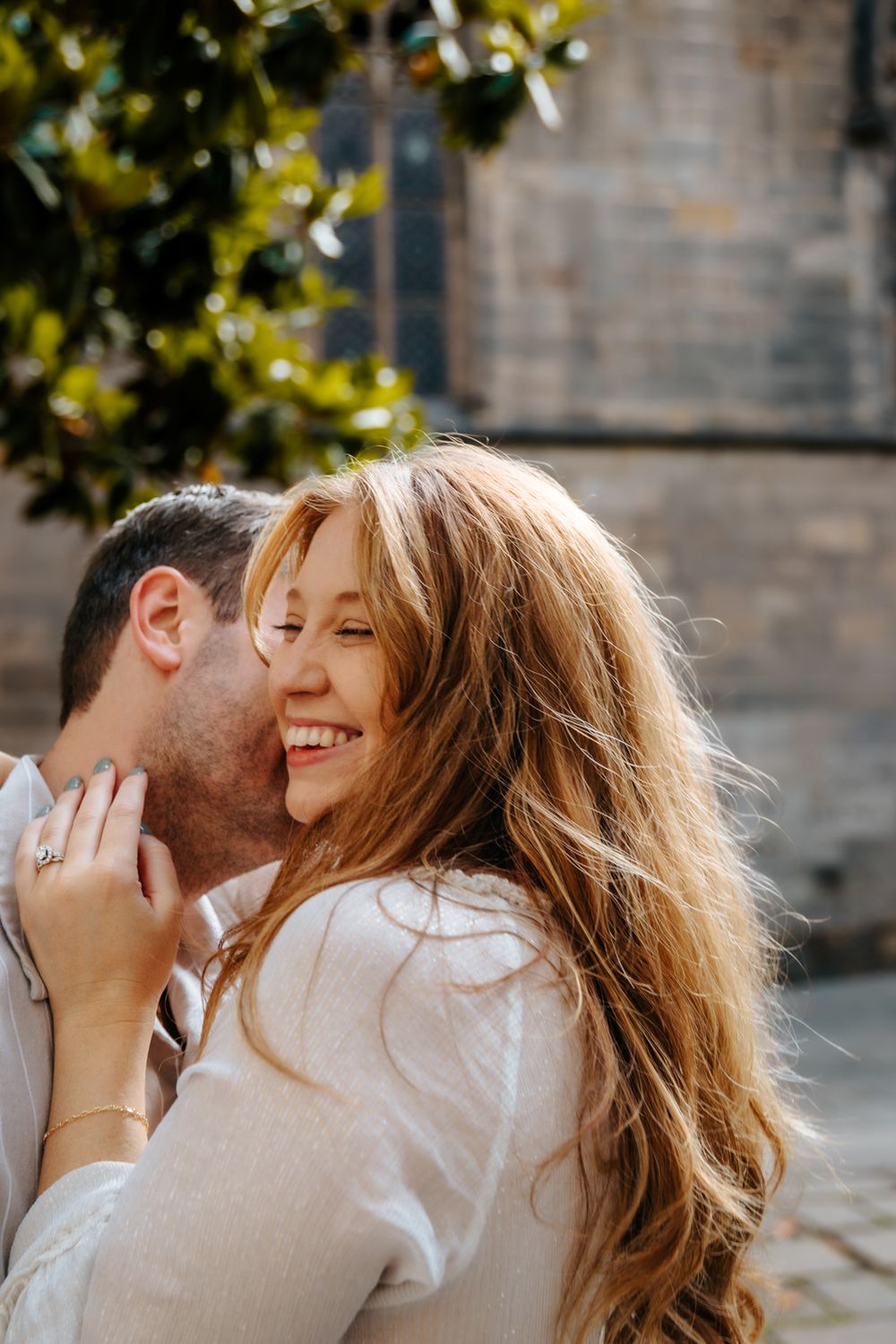 Expecting couple sharing laughter during their maternity session in the historic Old City of Barcelona.