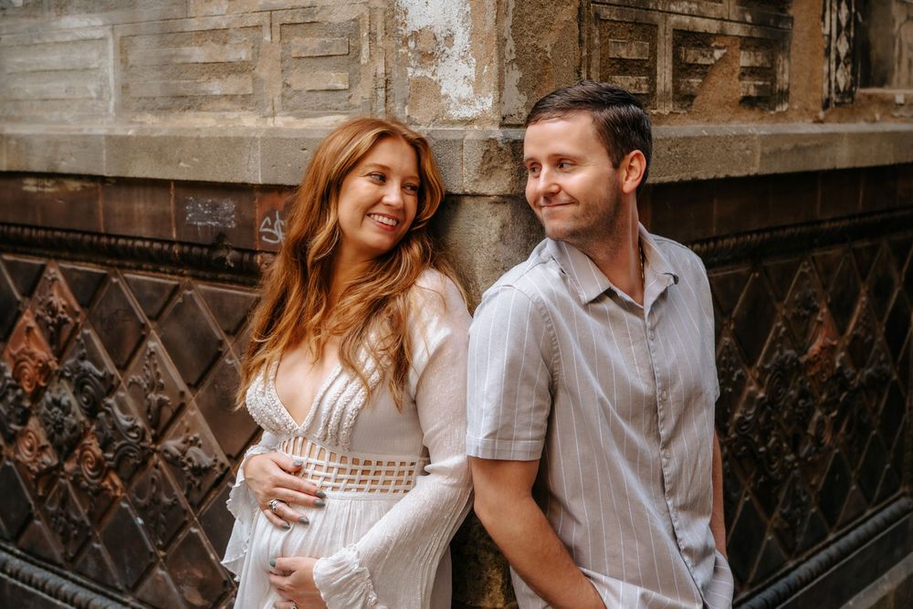 Kayla holding her baby bump tenderly in the magical alleys of Old City Barcelona.