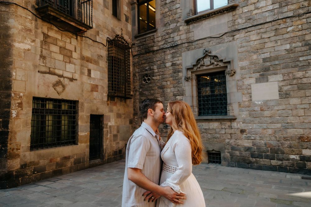 Kayla & Chad smiling together in the cobblestone streets of Old City Barcelona during their maternity photoshoot.
