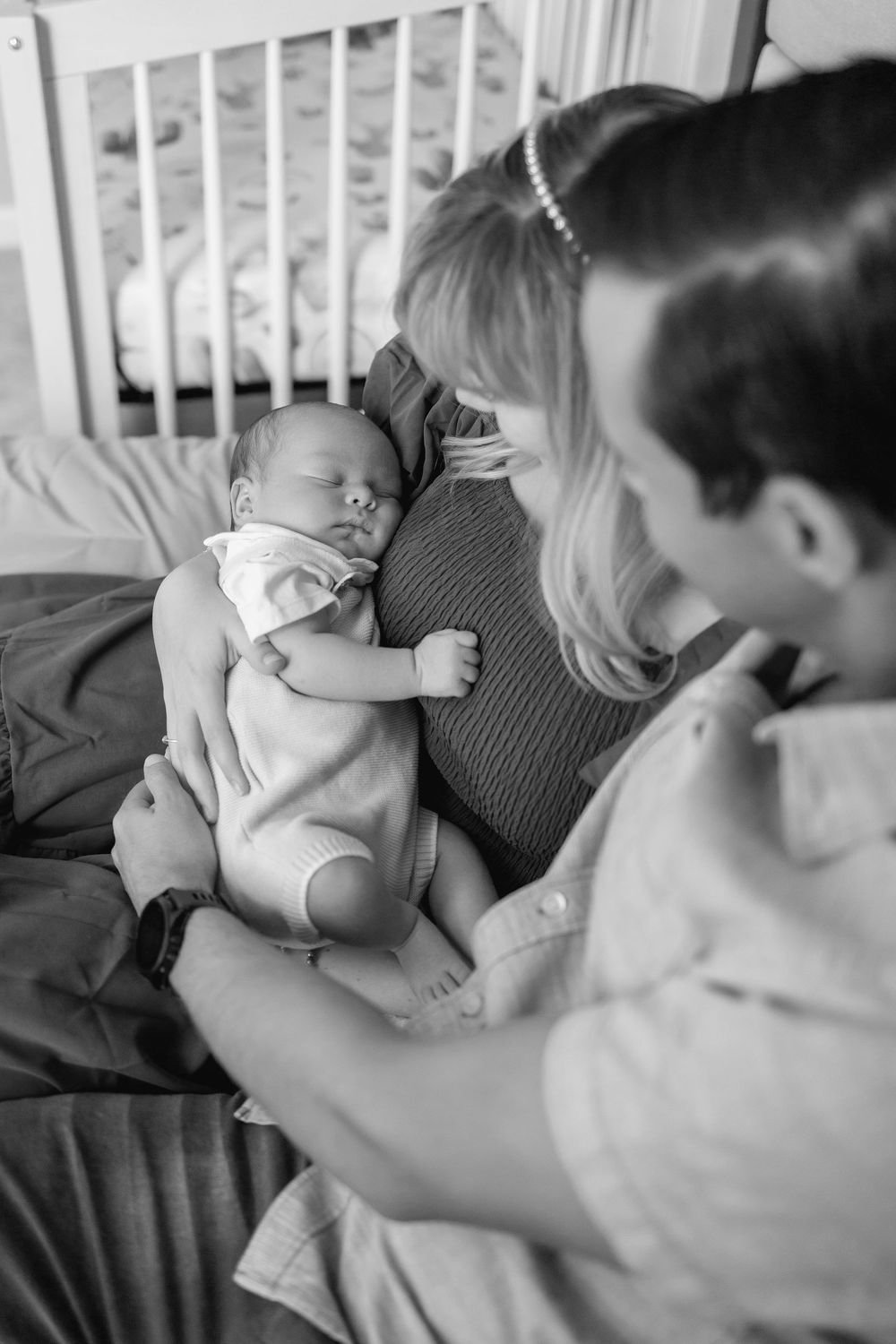 A series of black and white photos showing a baby resting and being held in a tender moment.