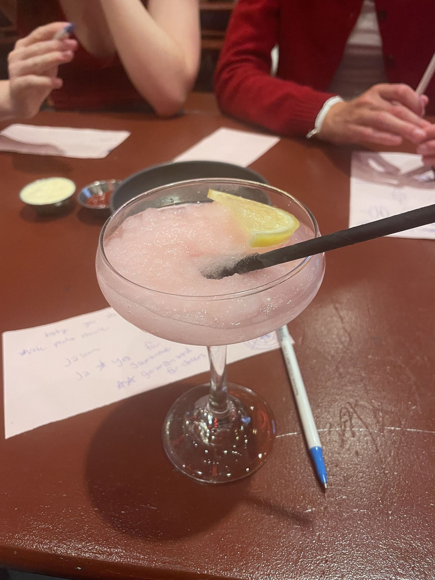 A closeup view of several pink martini cocktails garnished with fresh citrus slices served in classic glassware.