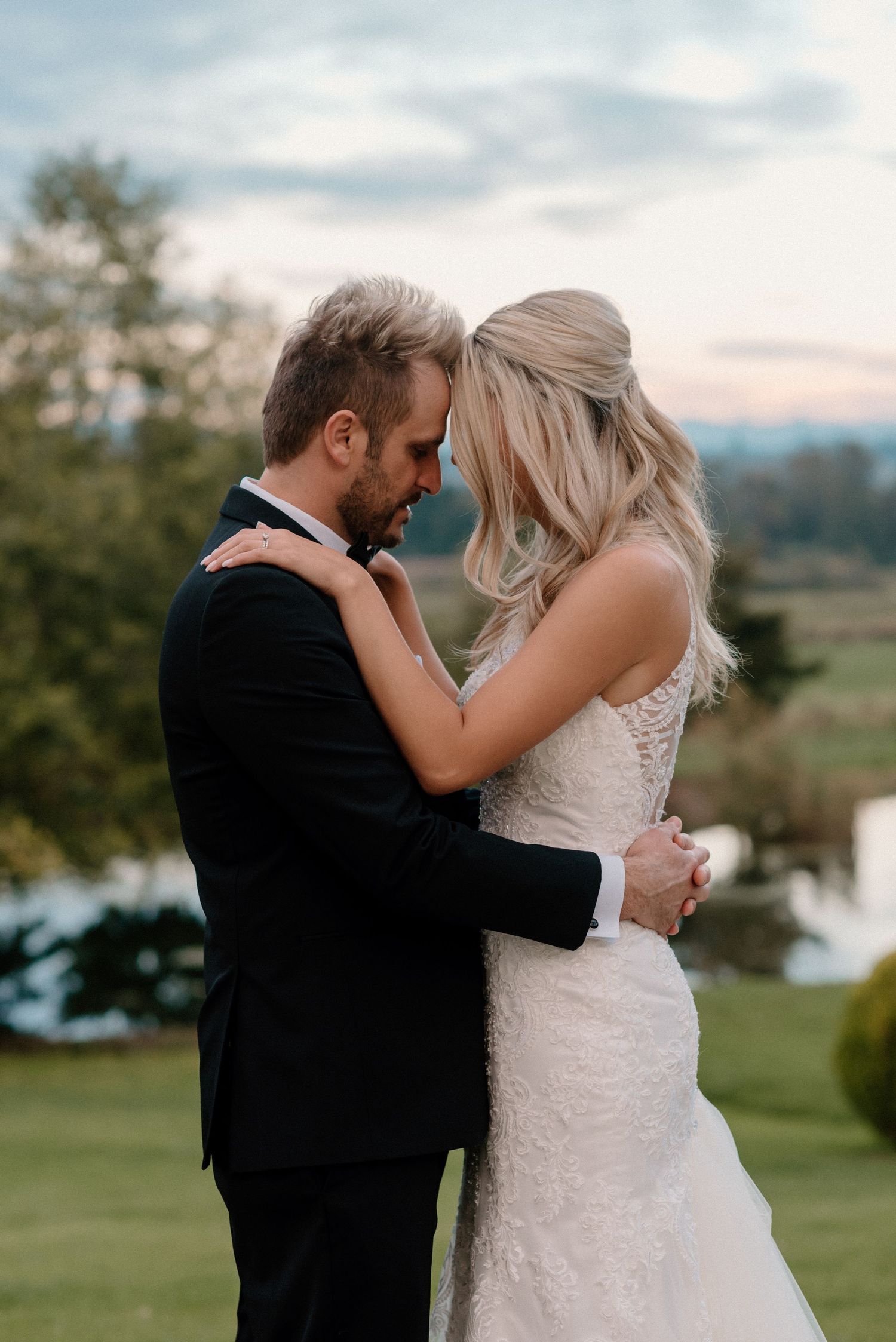 Romantic outdoor embrace on grassy hill during golden hour.
