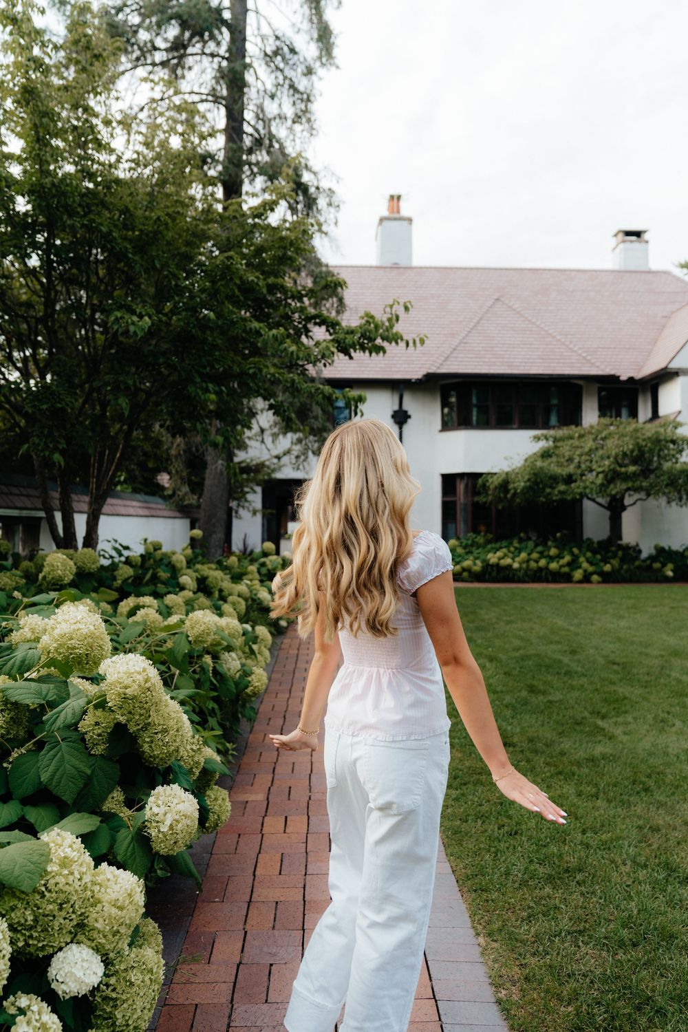 Dancing movements captured on a brick pathway surrounded by green landscaping and white architecture.